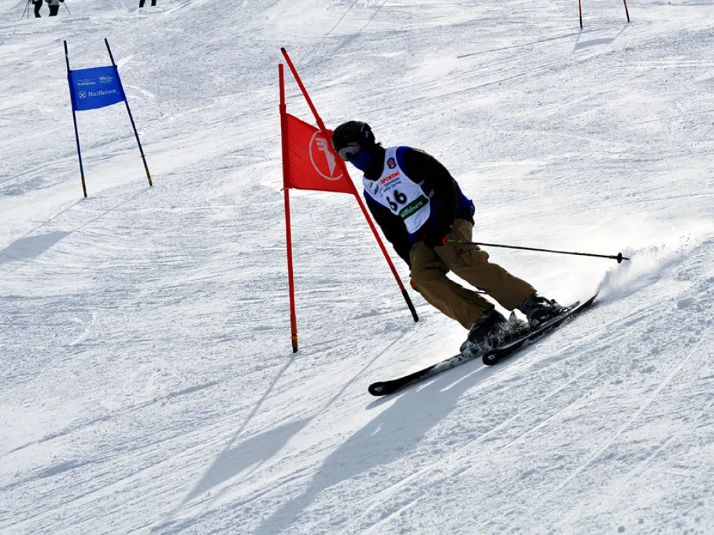 Skifahrer in beiger Hose umfährt das rote Tor.